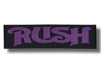 Peut inclure: Un écusson rectangulaire noir avec le mot "RUSH" brodé en violet dans une typographie stylisée. L'écusson a une bordure noire et est probablement thermocollant ou à coudre, adapté aux vêtements ou accessoires.