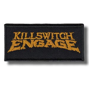 May include: A rectangular black patch with the words "KILLSWITCH ENGAGE" embroidered in gold thread. The text has a stylized, slightly distressed appearance. The patch is likely designed to be sewn or ironed onto clothing or accessories.