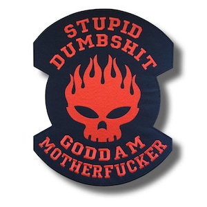 May include: A navy blue patch with a red skull design and the words "STUPID DUMBSHIT GODDAM MOTHERFUCKER" in red block letters. The patch has a unique shape with curved edges.