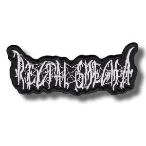 Puede incluir: Un parche bordado en blanco y negro con el texto "RECTAL SORECHIA" en una fuente gótica. El parche tiene un borde negro y un diseño blanco similar a una telaraña dentro de las letras. Para ropa o accesorios.