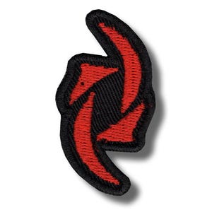 May include: Embroidered patch featuring a stylized red arrow design on a black background. The patch has a black border and is likely intended for application on clothing or accessories. The design is a bold, eye-catching graphic.