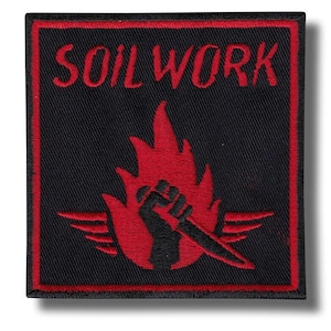 Puede incluir: Parche cuadrado negro con borde rojo y texto "SOIL WORK". El parche presenta un diseño de llama roja con un puño negro sosteniendo un cuchillo. El parche tiene forma cuadrada.