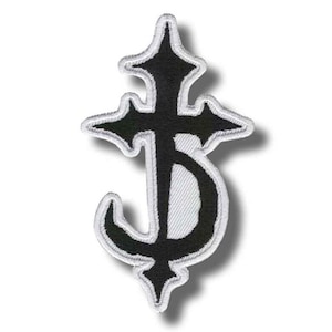 May include: Black and white embroidered patch featuring a stylized cross design. The patch has a black central shape with a white border, creating a high-contrast appearance. The design is symmetrical and detailed, suitable for clothing or accessories.