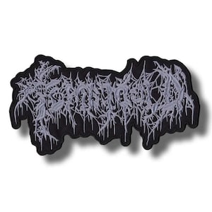 May include: A black embroidered patch with the word "SCUMFUCKED" in a stylized, gothic font. The text is in a light gray color and has a dripping, textured effect. The patch has a black border.
