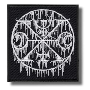 Op de afbeelding: Zwart vierkantige patch met een wit, gedetailleerd cirkelvormig ontwerp. Het ontwerp bevat een centraal symbool en druipende elementen. De patch is geborduurd, geschikt voor kleding of accessoires.