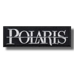 May include: A black rectangular embroidered patch featuring the word "POLARIS" in white capital letters. The text is bisected by a white horizontal line. The patch has a black border and a shadow.