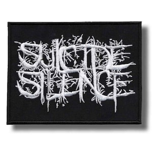 Könnte beinhalten: Schwarzer rechteckiger Aufnäher mit dem weißen, gestickten Schriftzug "SUICIDE SILENCE". Der Schriftzug ist in einem gotischen Stil mit detaillierten, wurzelartigen Verzierungen gehalten. Für Kleidung oder Accessoires.