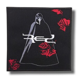 Puede incluir: Parche cuadrado negro con un diseño bordado. El diseño presenta una figura con una capa con capucha, la palabra "Red" en blanco y hojas de arce rojas. La figura es gris y las hojas son rojas.