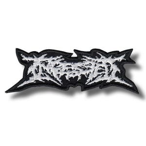 May include: Embroidered patch featuring white, stylized text on a black background. The text has a jagged, distressed appearance. The patch is rectangular with pointed edges. Suitable for application on clothing or accessories.