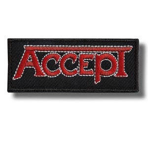 May include: A rectangular black patch with the word "ACCEPT" embroidered in red, outlined with white stitching. The patch is likely for clothing or accessories, showcasing a band's logo.