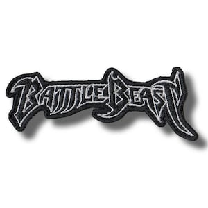 Könnte beinhalten: Ein schwarzer, gestickter Aufnäher mit dem Schriftzug "BATTLE BEAST" in einer stilisierten, gotischen Schriftart, umrandet in Weiß. Der Text hebt sich deutlich vom schwarzen Hintergrund ab. Der Aufnäher hat eine einzigartige, gezackte Form.