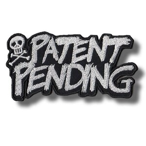 Op de afbeelding: Zwart geborduurd embleem met de witte tekst "PATENT PENDING" in een opvallend lettertype. Een schedel met gekruiste botten staat links. Het embleem heeft een zwarte rand, geschikt voor kleding of accessoires.