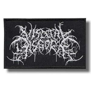 May include: Black rectangular patch with white embroidered text. The text is stylized in a gothic font, with a dripping effect. The patch is likely for a band or clothing item.