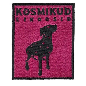 以下が含まれることがあります： マゼンタ色の背景に黒い犬のシルエットが刺繍されたパッチ。犬には花型の模様があります。パッチの上部には黒い文字で「KOSMIKUD EIROOSID」と書かれています。パッチは長方形で、黒い縁取りがあります。