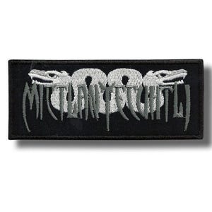 Puede incluir: Parche rectangular negro con el texto "MILITANT CHILD" en una fuente estilizada. El texto es blanco y gris, con dos criaturas parecidas a dragones que flanquean la palabra "800". El parche tiene un borde negro.