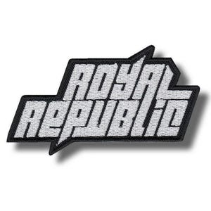 May include: Embroidered patch with the words "ROYAL REPUBLIC" in white block letters. The text is set against a black background with a unique angular shape. The patch is likely designed to be ironed or sewn onto clothing or accessories.