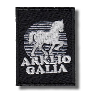 May include: Black rectangular patch featuring a white embroidered horse silhouette within a striped circle. The text "ARKLIO GALIA" is embroidered in white below the horse.