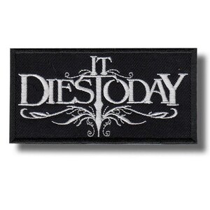 May include: A black rectangular patch featuring the white embroidered text "IT DIES TODAY" in a gothic font. The design includes decorative flourishes beneath the text. The patch is likely intended for application on clothing or accessories.