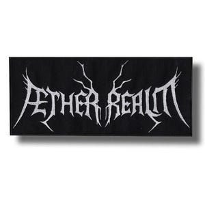 Może przedstawiać: Czarna prostokątna naszywka z białym napisem "AETHER REALM" w stylizowanej, gotyckiej czcionce. Tekst ma ostre, kanciaste krawędzie i jest wyśrodkowany na naszywce. Do odzieży lub akcesoriów.
