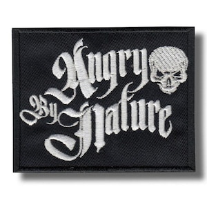 Pode incluir: Patch bordado preto com a frase "Angry by Nature" em fonte gótica, acompanhado por um gráfico de caveira. O patch tem formato retangular e uma borda preta.