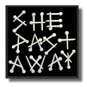 Könnte beinhalten: Schwarzer quadratischer Aufnäher mit weiß gesticktem Text „SHE ATE AWAY“. Die Buchstaben werden durch Nägel gebildet. Der Aufnäher hat einen schwarzen Rand und einen weißen Hintergrund.