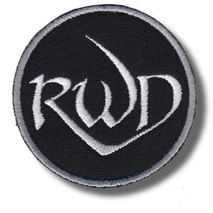 Può includere: Una toppa rotonda ricamata nera con le lettere "RWD" in un carattere bianco stilizzato. La toppa ha un bordo grigio ed è adatta per abbigliamento o accessori.