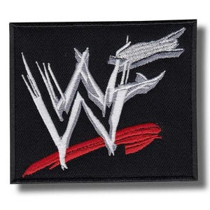 Könnte beinhalten: Schwarzer quadratischer Aufnäher mit den weißen stilisierten Buchstaben "WWF" und einem roten Pfeil. Der Aufnäher ist mit einem weißen und roten Design bestickt. Der Aufnäher ist wahrscheinlich für Kleidung oder Accessoires.