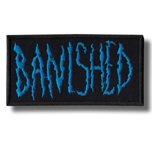 Puede incluir: Parche rectangular negro con la palabra "BANISHED" bordada en azul, con bordes irregulares. El parche tiene un borde negro y está diseñado para ropa o accesorios.