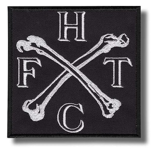 Puede incluir: Parche cuadrado negro con diseño bordado blanco. Presenta huesos cruzados y las letras H, F, T y C. El parche tiene un borde negro y una sombra.