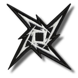 Puede incluir: Parche bordado en blanco y negro con un diseño de estrella estilizado. El parche tiene un fondo negro con un diseño blanco intrincado en el centro. La estrella tiene puntas afiladas y un centro cuadrado.