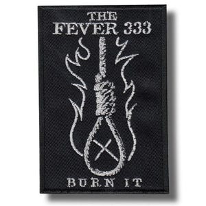 Może przedstawiać: Czarna prostokątna naszywka z białym haftowanym wzorem. Naszywka zawiera napis "THE FEVER 333" nad wizerunkiem pętli z płomieniami po obu stronach. Pod pętlą znajduje się napis "BURN IT".
