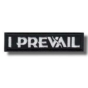 Może przedstawiać: Czarna prostokątna naszywka z wyhaftowanym białym napisem "I PREVAIL". Naszywka ma białą obwódkę i efekt cienia, sugerujący wypukły wzór. Naszywka jest prawdopodobnie przeznaczona na odzież lub akcesoria.