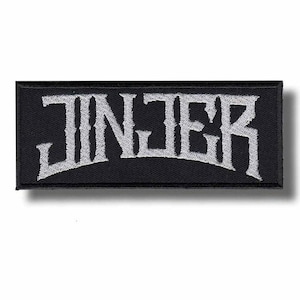 May include: Black rectangular patch with the word "JINJER" embroidered in white, stylized lettering. The patch has a black border and a slight shadow effect, suggesting a raised design. The patch is likely for clothing or accessories.