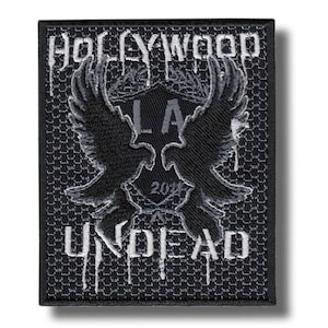May include: Black and gray embroidered patch featuring the text "HOLLYWOOD UNDEAD" with dripping font. The patch has a central emblem with "LA" and "2018" and two stylized bird wings.
