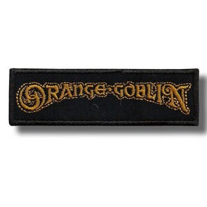 Op de afbeelding: Zwart rechthoekig embleem met de woorden "ORANGE GOBLIN" geborduurd in goudkleurig garen. De tekst is in een gestileerd lettertype en het embleem heeft een zwarte rand.