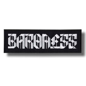 May include: A black rectangular patch featuring the word "BARONESS" in white gothic font. The patch is bordered in black and is designed to be sewn or ironed onto fabric. The patch measures approximately 10 cm in length.
