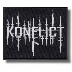 Puede incluir: Parche rectangular negro con la palabra "KONFLICT" bordada en blanco, estilizada con líneas verticales y horizontales. El parche tiene un borde negro y un efecto de sombra.
