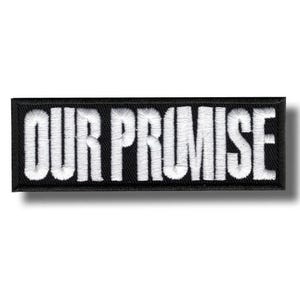Op de afbeelding: Een rechthoekige zwarte patch met de geborduurde tekst "OUR PROMISE" in het wit. De patch heeft een zwarte rand en een licht schaduweffect.