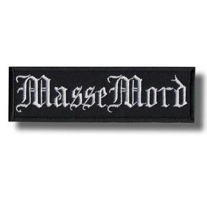 以下が含まれることがあります： 黒い長方形のパッチ。白いゴシック体の文字で「Masse Mord」と刺繍されています。 パッチには黒い縁取りがあり、衣服やアクセサリーに縫い付けたり、アイロンで接着したりするように設計されています。