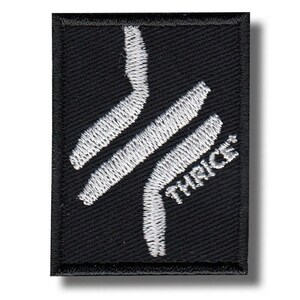 May include: Black rectangular patch with white embroidered design. The design features two parallel, curved lines and the word "THIRICE" in white, angled text. The patch has a black border and is likely an emblem or logo.