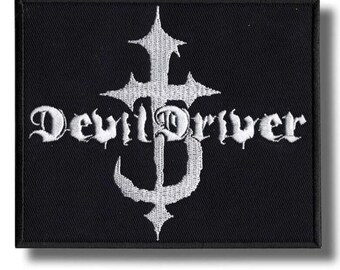 Peut inclure: Écusson rectangulaire noir avec texte brodé blanc et un motif de croix stylisée. Le texte "DevilDriver" est écrit en police gothique. L'écusson a une bordure noire et une ombre blanche.