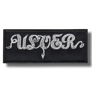 May include: Black rectangular patch with the word "USTER" embroidered in white, stylized script. The patch has a white border and a shadow effect.