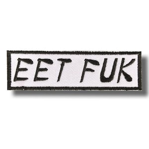 Könnte beinhalten: Rechteckiger, gestickter Aufnäher mit dem schwarzen Text "EET FUK" auf weißem Grund. Der Aufnäher hat einen schwarzen Rand und ist zum Aufnähen oder Aufbügeln auf Kleidung oder Accessoires gedacht.