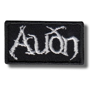 Könnte beinhalten: Schwarzer rechteckiger Aufnäher mit dem Wort "Avon" in weißer, gotischer Schrift gestickt. Der Aufnäher hat einen schwarzen Rand und ist zum Aufnähen oder Aufbügeln auf Kleidung oder Accessoires gedacht.