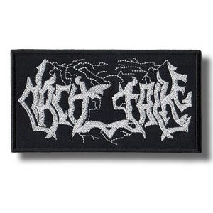 May include: Black rectangular patch with white embroidered text. The text appears to be a band name or logo in a stylized, gothic font. The patch has a clean, finished edge and is likely designed to be sewn onto clothing or accessories.