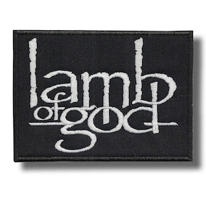 Può includere: Toppa rettangolare nera con la scritta ricamata bianca "Lamb of God". La toppa ha un bordo nero ed è probabilmente progettata per essere cucita su vestiti o accessori.