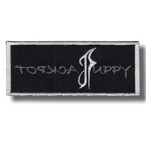 Puede incluir: Un parche rectangular negro con texto bordado blanco y un borde blanco. El texto dice "JACKPOT PUPPY" en una fuente estilizada. El parche tiene una apariencia texturizada.