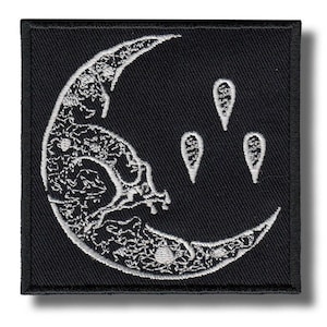 Op de afbeelding: Zwart vierkantige patch met een wit maansikkeldessin, gedetailleerd met bloempatronen en drie druppelvormen. De maan heeft een schedelachtig uiterlijk. Geschikt voor kleding of accessoires.