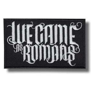 Puede incluir: Parche rectangular negro con las palabras "WE CAME AS ROMANS" bordadas en blanco con letras góticas. El parche tiene un borde negro y un efecto de sombra.