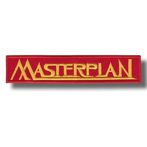 May include: A red embroidered patch with the word "MASTERPLAN" in gold thread. The rectangular patch is designed for application on clothing or accessories. The gold text is centered on the red background, creating a clear contrast.